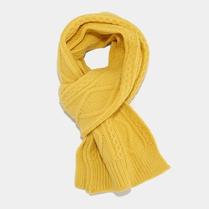 Detailed macro view of the bright yellow cable knit scarf with thick winter texture