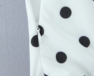 Détail de la fermeture éclair invisible sur une robe blanche à pois noirs