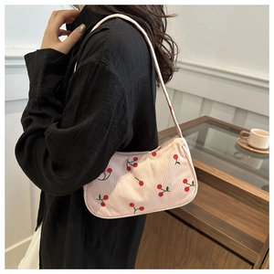 Pink corduroy underarm bag with strawberry print shown worn on a model in a cozy setting