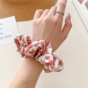 Detailed close-up of floral fabric hair scrunchie with red and pink flower patterns