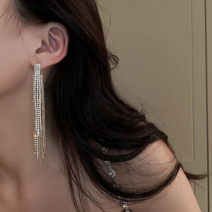 Elegant gold long tassel earrings with sparkling rhinestones worn by a model