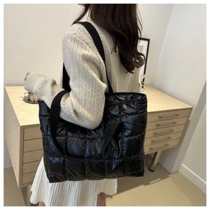 Side view of model wearing a black puffer tote bag with diamond quilted stitch pattern