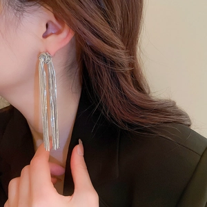 Close-up of elegant silver knot earrings with long tassels on a female model