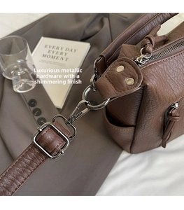 Close-up of shiny silver metal hardware and lychee grain leather on a brown tote bag