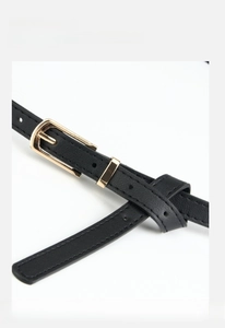 Close-up of black PU leather skinny belt with golden pin buckle and litchi texture
