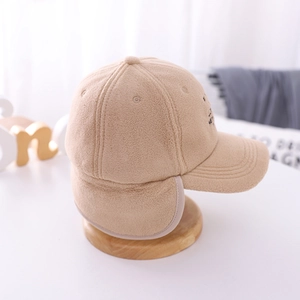Detailed view of beige fleece baseball cap featuring fold-down earflaps and side embroidery