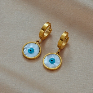 Golden earrings with blue evil eye pendant on elegant silk background for women
