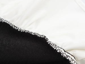 Détail de couture entre un tissu blanc lisse et un tissu noir à côtes fines