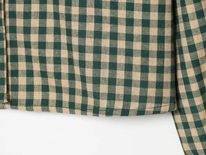 Macro detail of the green and yellow plaid shirt showing fine stitching and fabric texture