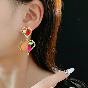 Primo piano di orecchini a cuore vintage in oro con strass colorati su una modella