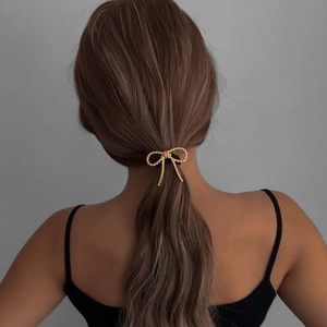 Golden bow knot hair tie with metallic texture shown on a female ponytail hairstyle
