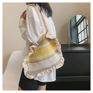 Detailed view of hand-knitted striped tote bag with ruffled edges on shoulder