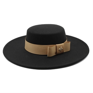 Detail of black wool fedora with gold satin ribbon and metallic bee ornament