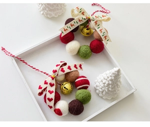 Detail der Weihnachts-Filzkugelkranz mit goldenen Glocken und festlichem Schleifenband