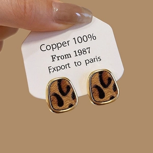 Gros plan de boucles d'oreilles carrées imprimé léopard dorées en matériau 100% cuivre