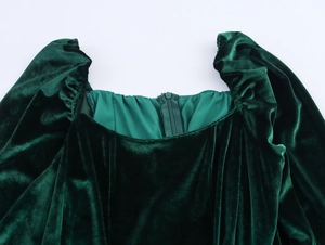 Detail of square neckline on dark green velvet dress with pleated puff sleeves and zipper
