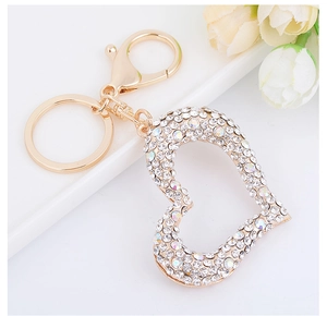 Close-up of golden heart keychain with sparkling rhinestones on a white floral background