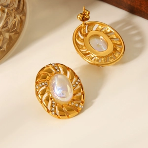 Dettaglio di orecchini vintage in oro 18k con perla e strass scintillanti sul metallo