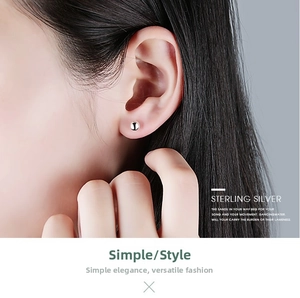 Detailed view of a minimalist S999 sterling silver ball stud earring on model's ear