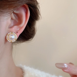 Close-up of elegant gold earrings featuring large central pearl and small pearl halo