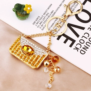 Macro detail of envelope-shaped golden pendant with yellow crystals on beige silk fabric