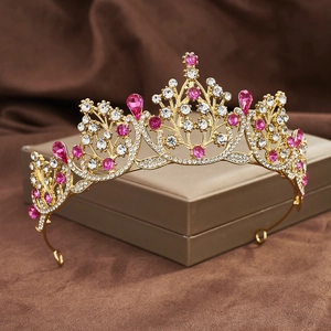 Detailed view of a golden baroque crown with pink teardrop gems on a gift box