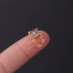 Macro view of a gold heart cartilage stud with pink gem and dangling fine chain