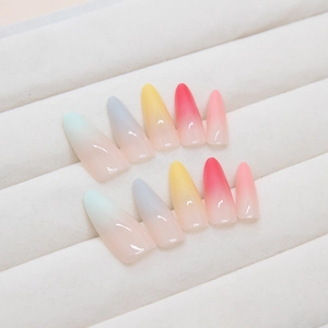 Rainbow gradient almond shape press-on nails in 10-piece set on a cream velvet tray