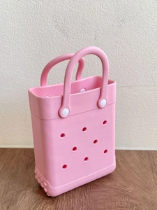 Detailed close-up of pink EVA beach tote bag with perforated hole design on wood surface