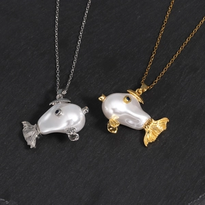 Detail of silver and gold fish necklaces with pearls on dark slate background
