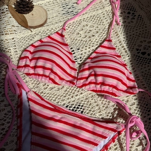 Dettaglio flat lay di bikini in spugna a righe rosse e rosa su sfondo di pizzo