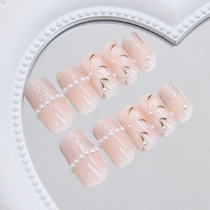 Faux ongles dégradé rose avec motifs floraux et détails de perles élégantes