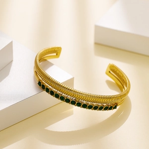 Golden double-layer fish pattern cuff bracelet with green zircons on white platform