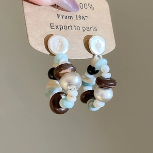 Detail of beaded hoop earrings with star-etched studs and multi-colored resin pearls