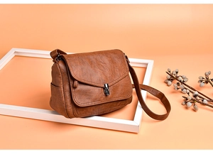 Close-up of brown litchi pattern leather shoulder bag with vintage metal turn-lock closure