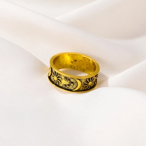 Vintage gold sun moon and star embossed metal ring on white satin background