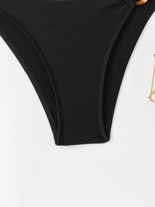 Close-up of black bikini bottoms with tortoise shell ring detail and double stitching