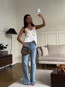 Vue détaillée du caraco en dentelle et satin blanc avec un jean bleu clair