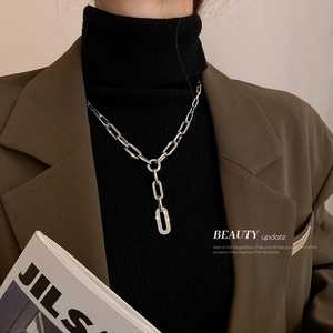 Détail d'un collier en Y argenté orné de zircons porté sur un pull noir élégant