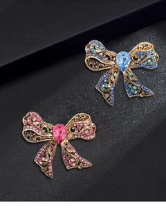Detail of vintage bronze bow brooches with blue and pink teardrop rhinestones