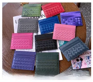 Close-up of woven sheepskin leather card holders in various colors on a wooden table
