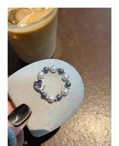 Detail of beaded ring with purple heart zircon and elegant white and grey pearls