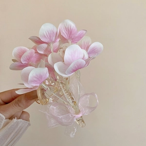 Detailed close-up of pink fabric flower hair claw clip with delicate organza ribbon bow