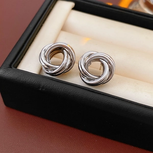 Détail de boucles d'oreilles nœuds argentées présentées dans un coffret à bijoux noir