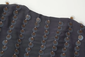 Detail shot of dark grey fabric featuring layered sequins and fine ribbed texture
