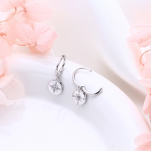 Detailed close-up of S925 silver starburst earrings and compass charm with zircon stones