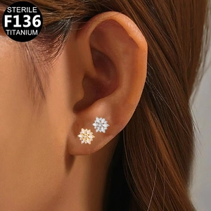 Macro detail of F136 titanium flower stud earrings with zircon in gold and silver