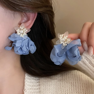 Macro detail of layered dusty blue fabric flower earrings with faux pearl embellishments