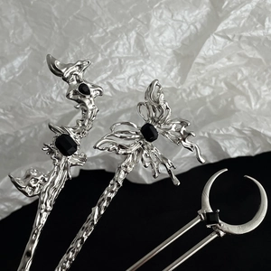 Close-up of silver tassel hairpins featuring butterfly, crescent moon, and abstract metal shapes