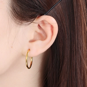 Macro shot of minimalist 18K gold plated stainless steel hoop earring on model ear